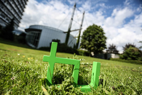 In the foreground one can see the green TU logo on the grass and in the background there is the Mathetower.